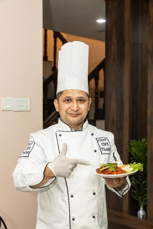 Our head chef in whites, holding a plated dish