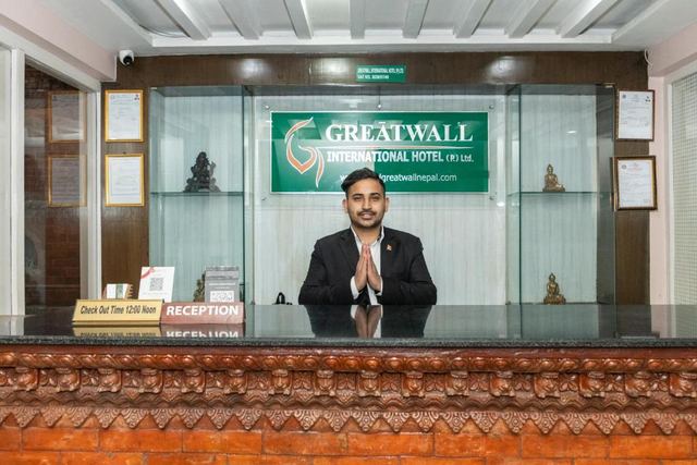 Reception desk with a carved wooden counter and a staff member greeting guests