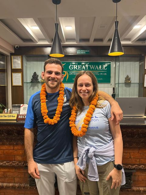 A smiling couple with marigold garlands at the reception