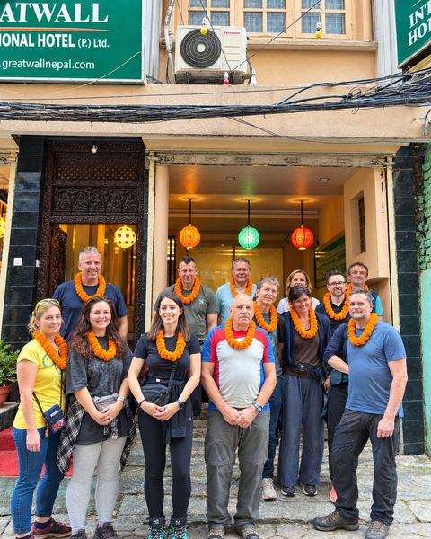 A large group of guests with marigold garlands outside the hotel entrance
